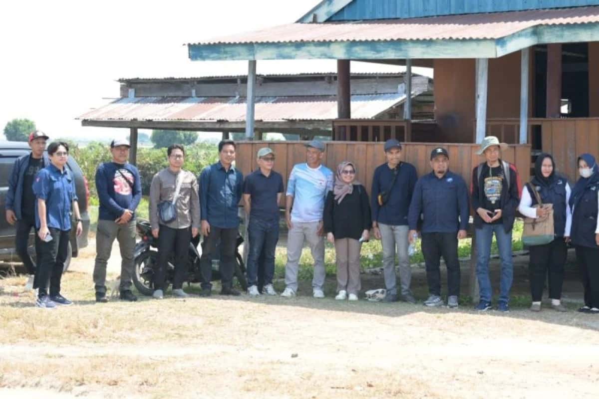 Anggota tim survei berdiri bersama di depan bangunan dekat kawasan tambak